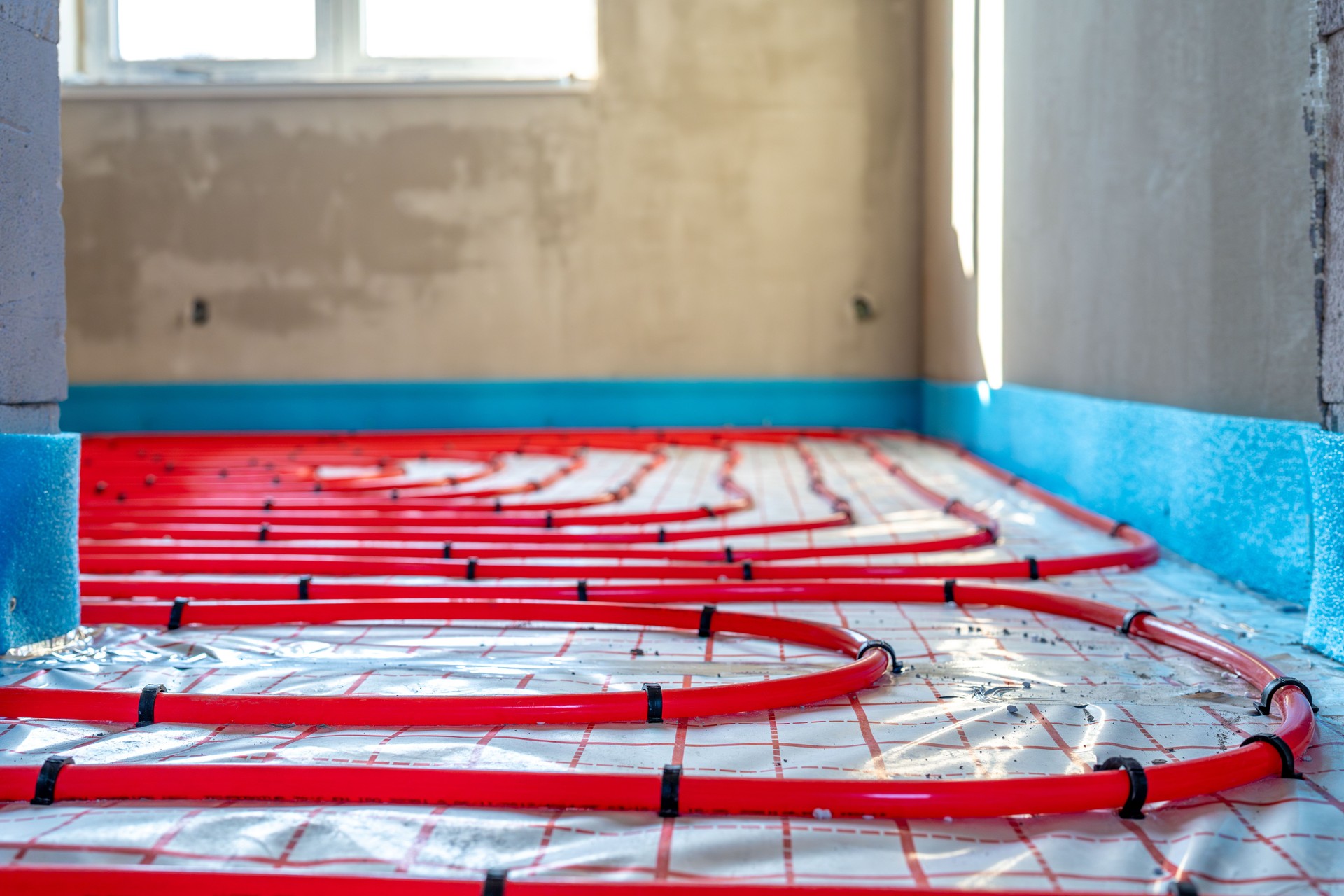 Installation einer Fußbodenheizung mit roten Rohren in einem neuen Haus